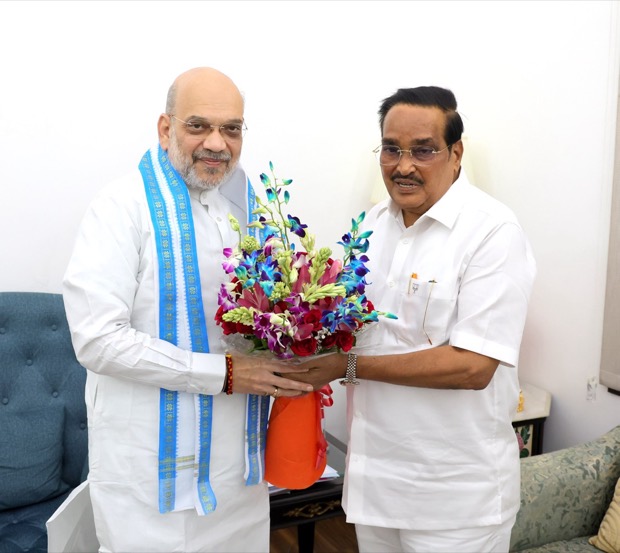 C. R. Patil and the Union Home Minister holding a flower arrangement between them at a meeting.
