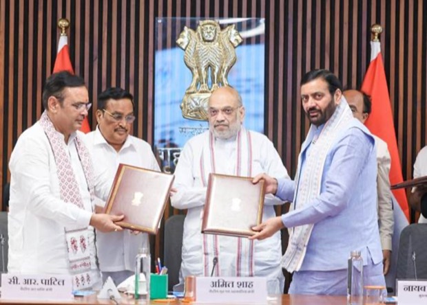 C. R. Patil exchanging a signed folder with the Union Home Minister across a formal government table, beneath the State Emblem of India.