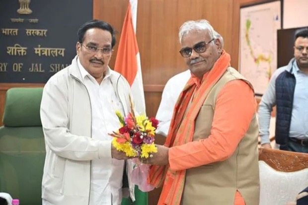 C. R. Patil receiving a bouquet from a visitor at the Ministry of Jal Shakti, with the ministry's name board and the national flag behind them.