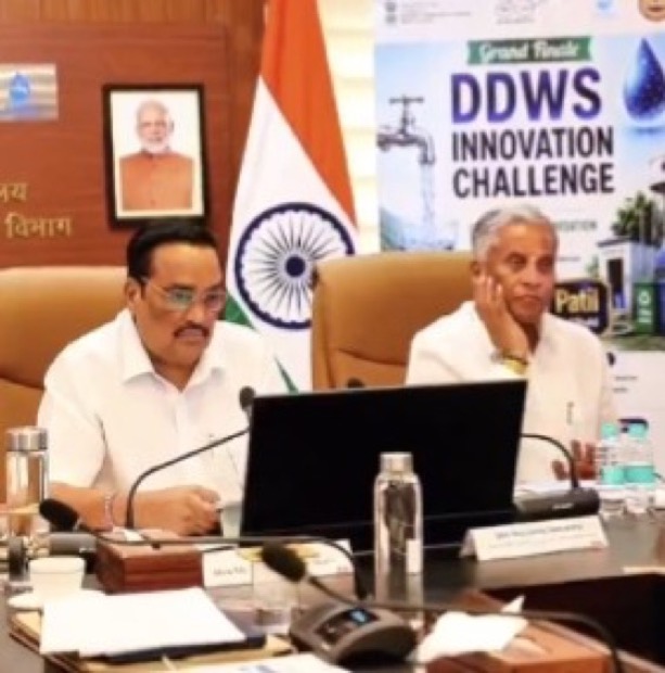 C. R. Patil seated at a conference table chairing an event, with a banner for a Department of Drinking Water and Sanitation innovation challenge and the national flag behind him.