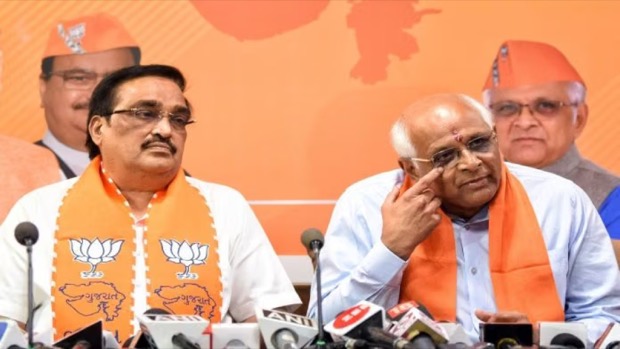 C. R. Patil at a press conference alongside the Chief Minister of Gujarat, with microphones on the table in front of them.