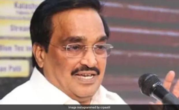 C. R. Patil speaking into a microphone at an event, gesturing with one hand.