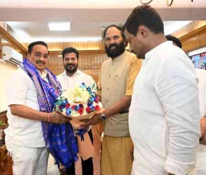 C. R. Patil, wearing a shawl, receiving a bouquet from visitors at an official meeting indoors.