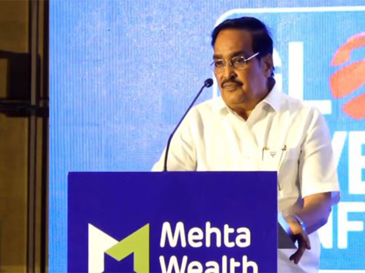 C. R. Patil speaking from a lectern at an event, with a sponsor backdrop behind the stage.